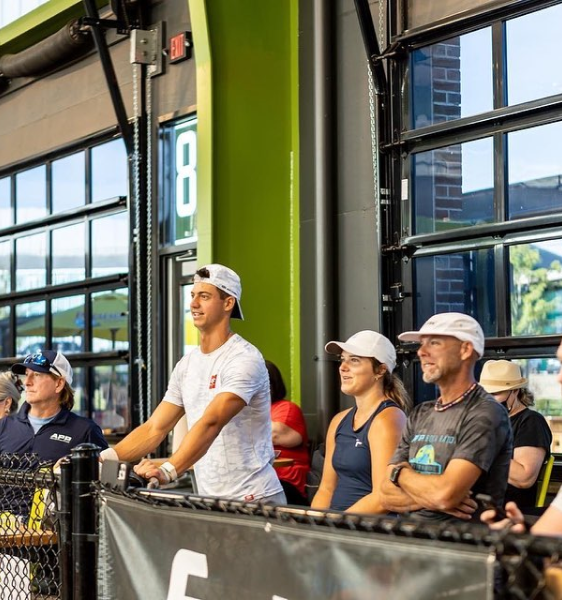 Image of people watching a Pickleball game from the courtside.