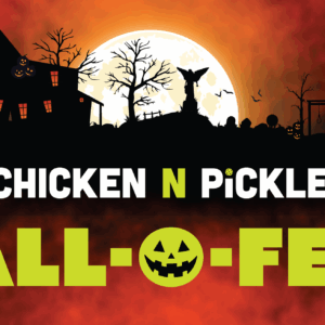 A spooky Halloween scene with haunted houses, leafless trees, jack-o-lanterns, and a full moon. Text reads Chicken N Pickle Hall-O-Fest with a jack-o-lantern face in the word Hall-O-Fest.