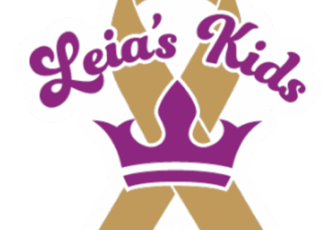 A gold ribbon with a purple crown at the base and the words Leias Kids in purple script across the top, symbolizing a giveback effort benefiting vets and youth.