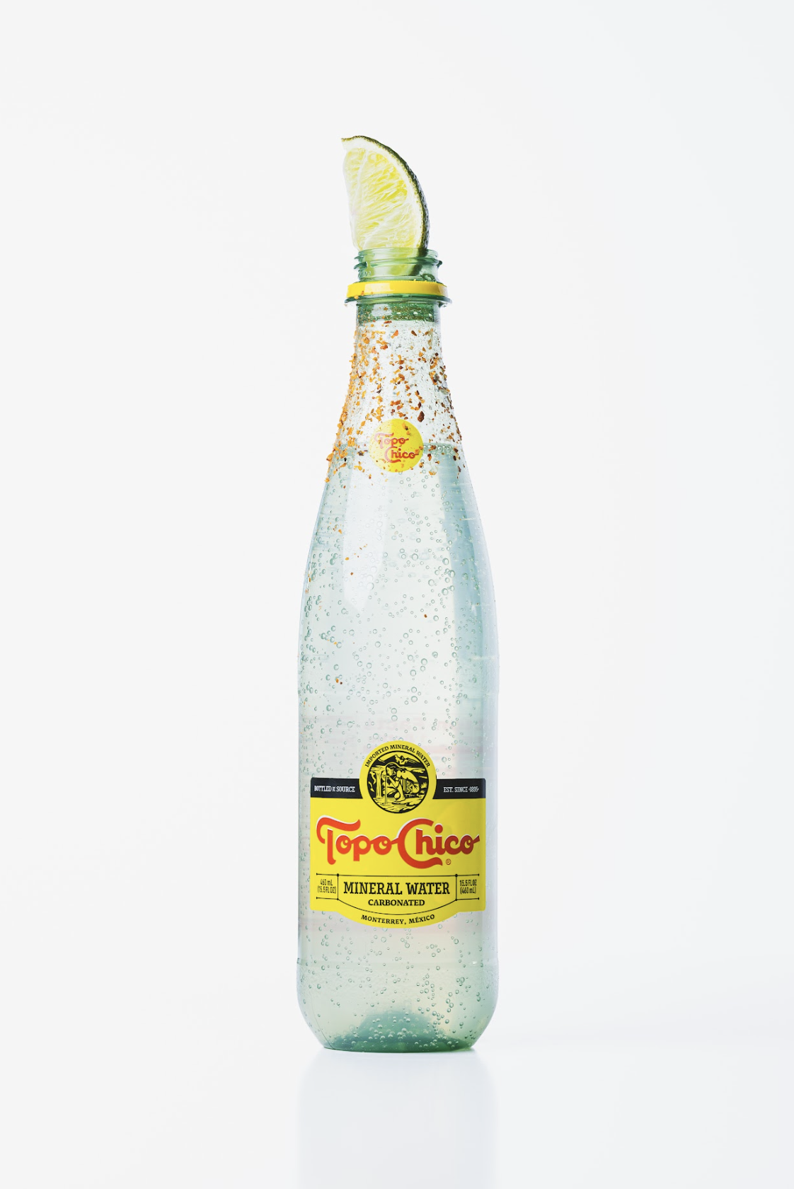 Ranch Water Cocktail inside of a Topo Chico Mineral Water Bottle with Tahin around the rim and a lime