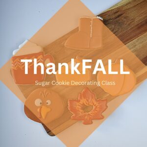 Four fall-themed sugar cookies (a boot, mug, turkey, and maple leaf) are displayed on a wooden board with the text ThankFALL Sugar Cookie Decorating Class overlayed in a translucent orange diamond.