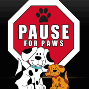 Two cartoon dogs sit in front of a red stop sign with a paw print at the top. The sign reads Pause for Paws. The background is black, making the sign and dogs stand out.
