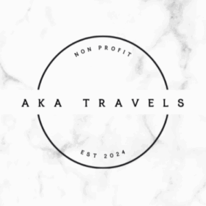 A minimalist white logo with a black circle. Inside, the text reads AKA TRAVELS in bold letters. Above, it says NON PROFIT, and below, EST 2024. The background has a subtle marble texture.