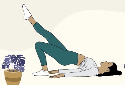 A woman lies on her back with one leg raised and the other bent, performing a bridge exercise. She wears teal leggings, a white top, and socks. A potted plant is placed nearby.