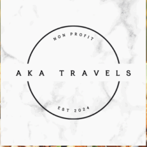 Logo with a white marble background, black circular outline, and AKA TRAVELS in the center. NON PROFIT is at the top, EST 2024 at the bottom—highlighting Giveback initiatives benefiting vets and youth inside the circle.