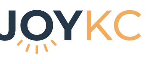 Logo reading JOY KC with JOY in dark blue and KC in orange. The O in JOY features yellow rays below it, resembling a rising sun. White background. Design celebrates Giveback Benefiting Vets for Youth.