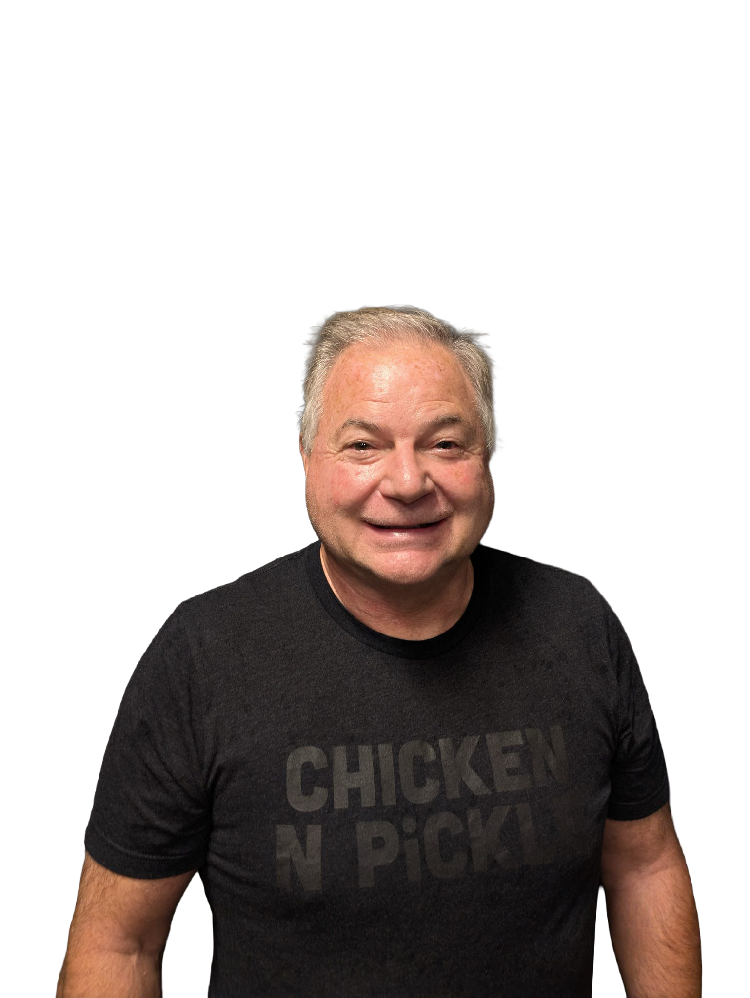 A smiling older man with gray hair wearing a black CHICKEN N PICKLE t-shirt stands against a plain white background.