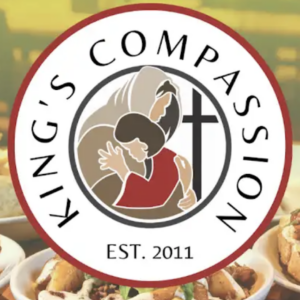 Circular logo for Kings Compassion featuring two people embracing, a large cross, and EST. 2011 text. Food dishes are blurred in the background, highlighting their giveback mission benefiting vets and youth in need.