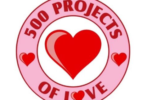 A pink circular badge with 500 Projects of Love written around a large red heart in the center, accented by three smaller red hearts—celebrating HELP of Southern Nevada Giveback Night.