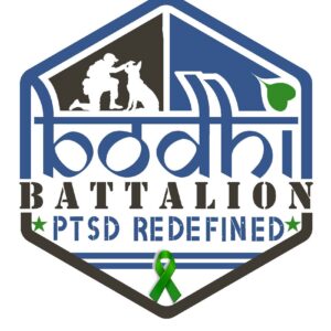 A hexagonal logo with a soldier kneeling beside a dog, the text bodhi BATTALION PTSD REDEFINED, a green awareness ribbon, and heart. Designed in blue, black, and green—benefiting vets for youth as part of our giveback mission.