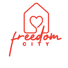 Red outline of a house with a heart in the center above the cursive word freedom and the word CITY in uppercase beneath it, all set against a white background.